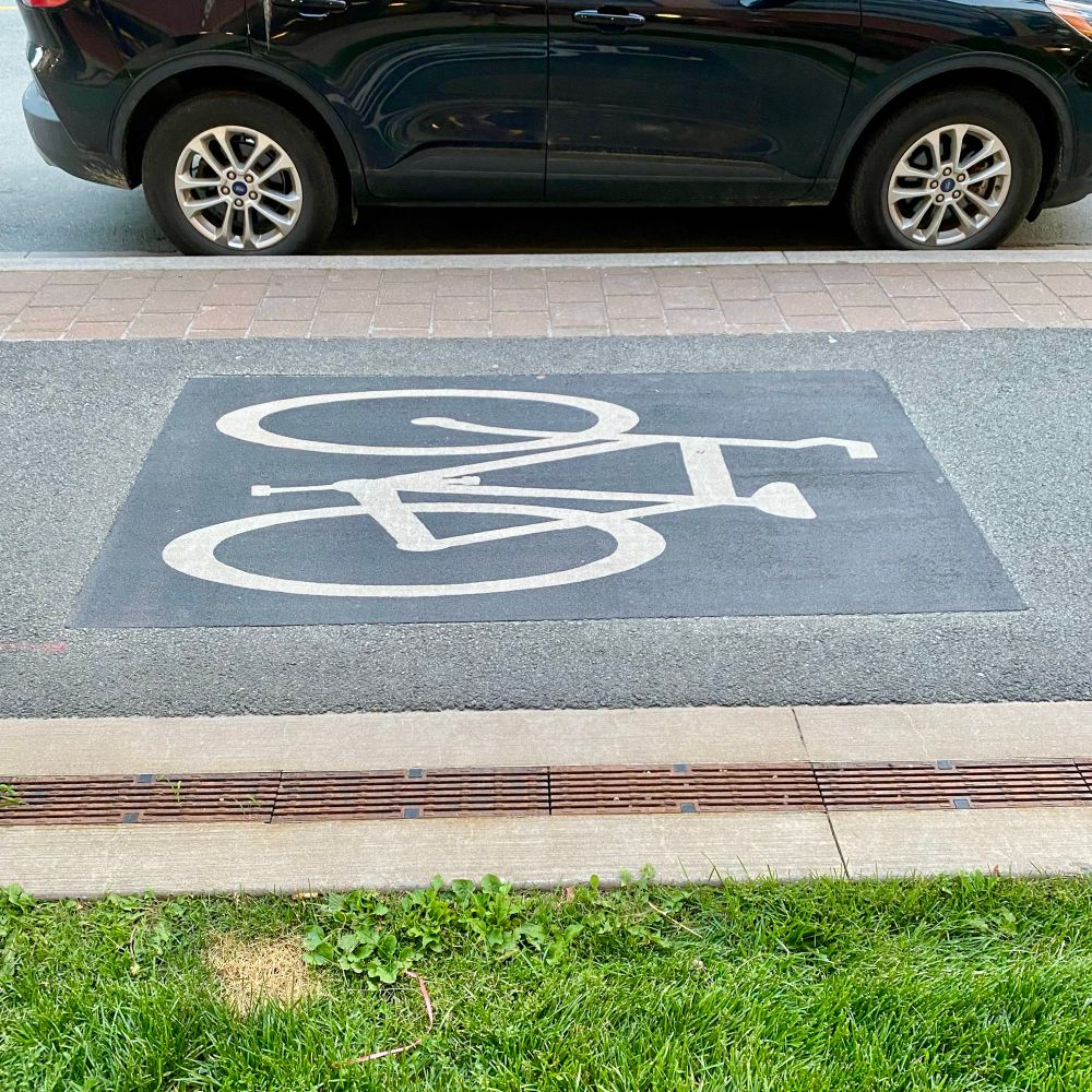 A bike lane pavement marking as seen by a pedestrian walking by.