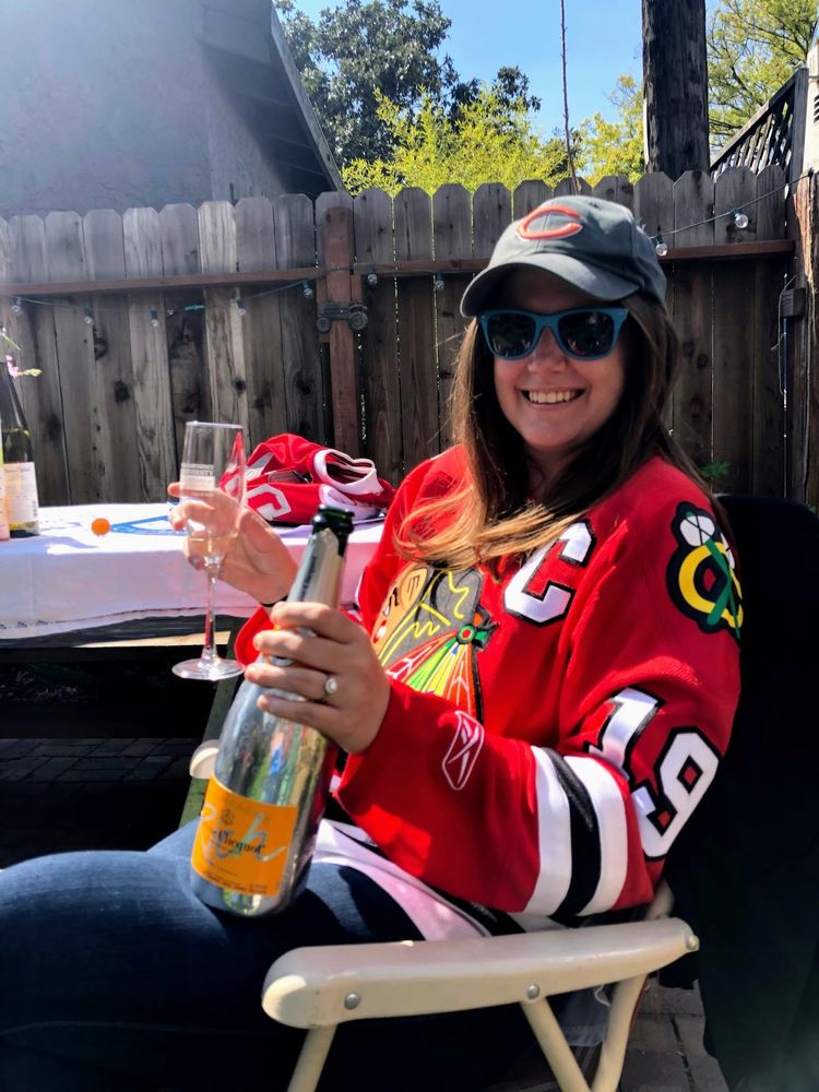 smiling in the sunshine in a blackhawks sweater and bears hat 