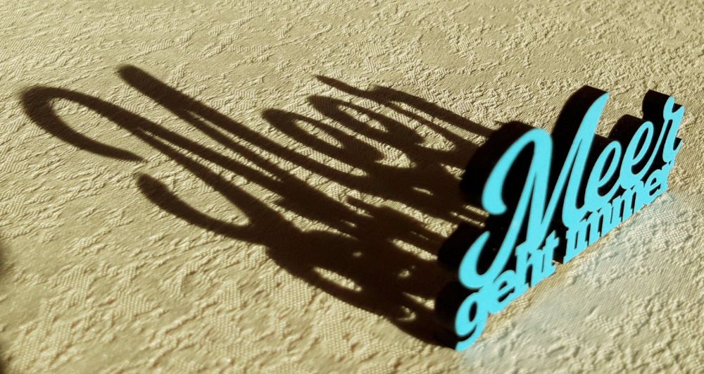 Das Foto zeigt einen plastischen Schriftzug "Meer geht immer", der hinter sich einen langen Schatten wirft.