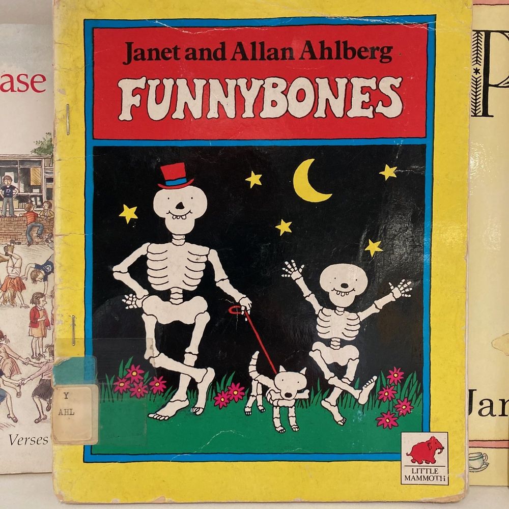 The front cover of Funnybones by Janet and Allan Ahlberg on a library shelf.
