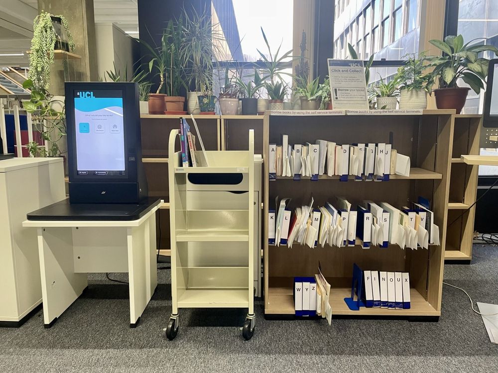 Click and Collect shelves next to a self-service machine with plants behind.