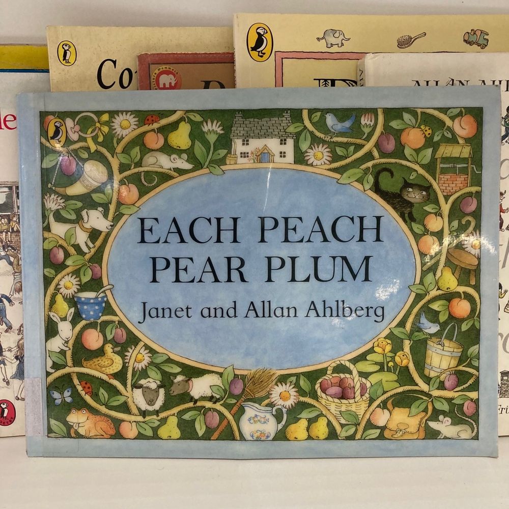 The front cover of Each Peach Pear Plum by Janet and Allan Ahlberg on a library shelf.
