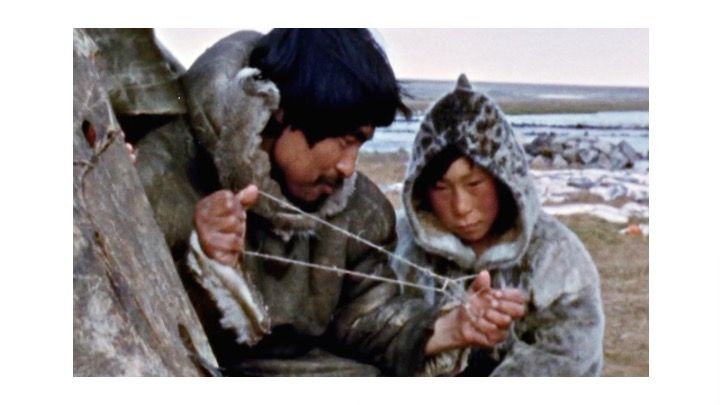 An image showing an Inuit father teaching his son how to fish from the Man: A Course of Study Curriculum Project by Jerome Bruner