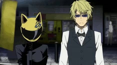 a man wearing sunglasses and a cat helmet stands next to another man in a suit