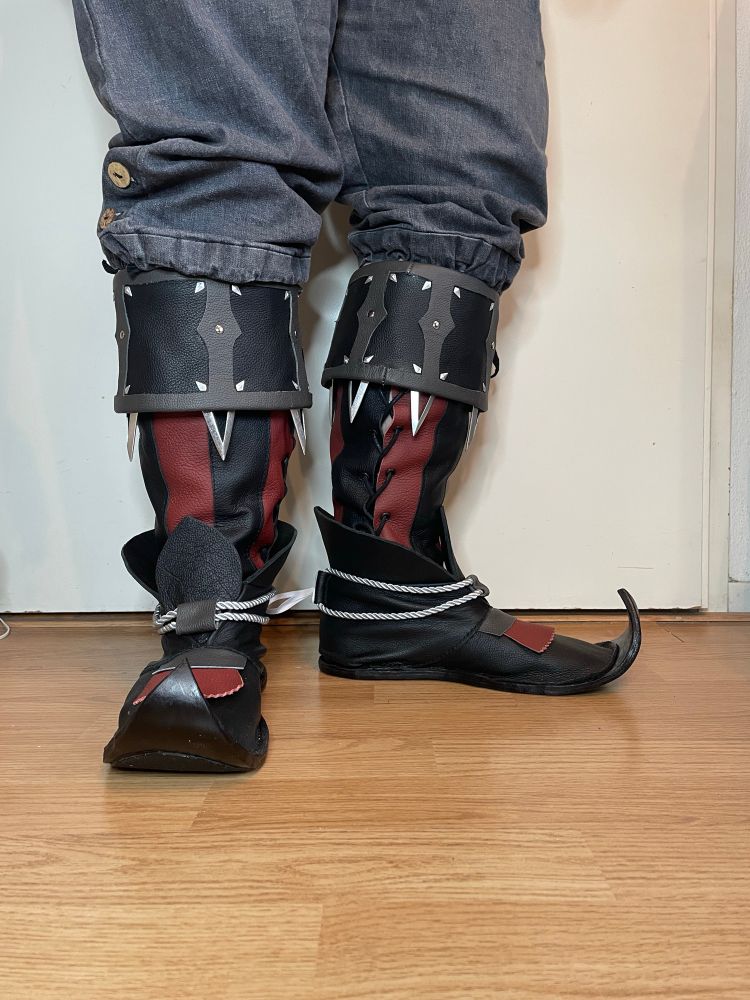 Me posing in my self made Raphael shoes. They are red with black with a grey collar. The toes of the shoes are curled. 
