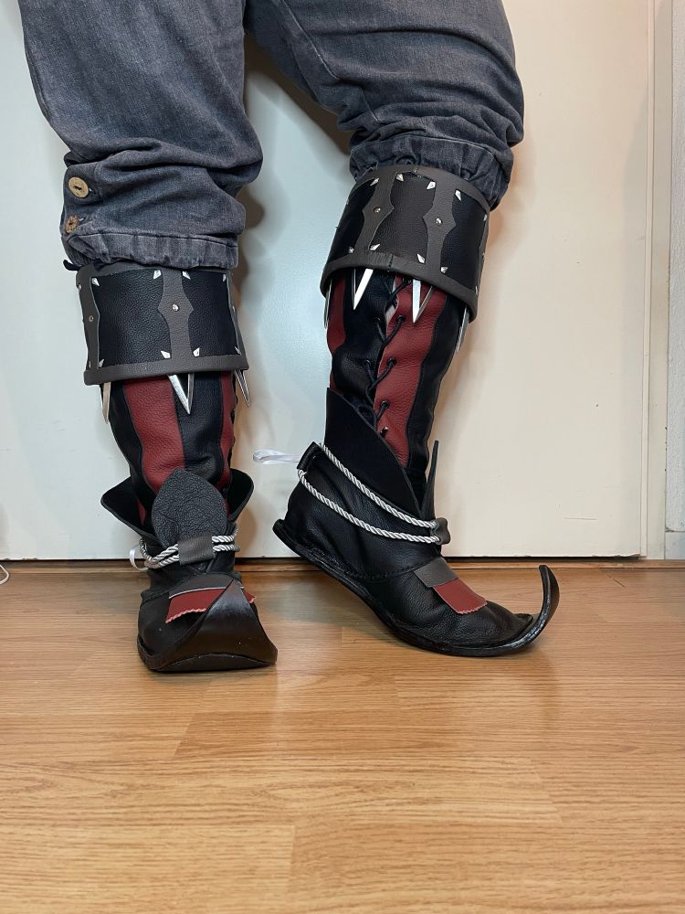 Me posing in my self made Raphael shoes. They are red with black with a grey collar. The toes of the shoes are curled. 
