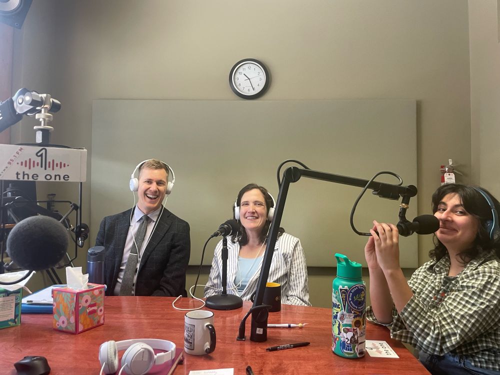 Three people at a radio station smiling