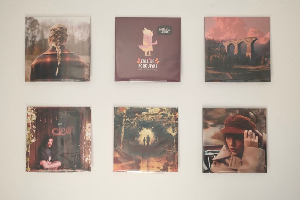 Two rows of vinyl records hanging on a wall. From the top left to bottom right: Taylor Swift - Evermore, Pinsel - The Fall of Porcupine, Spencer Doran - Season, Soccer Mommy - Clean, Gustavo Santaollala - The Last of Us, Taylor Swift - Red