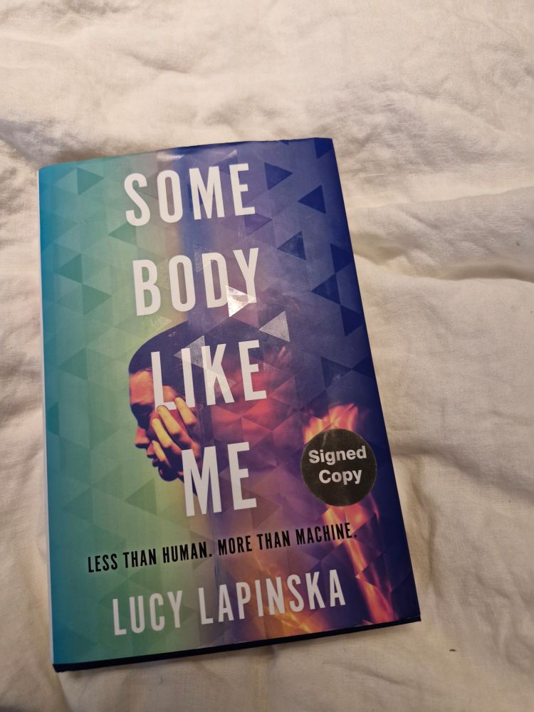 Copy of Some Body Like Me by Lucy Lapinska laying on a duvet. 