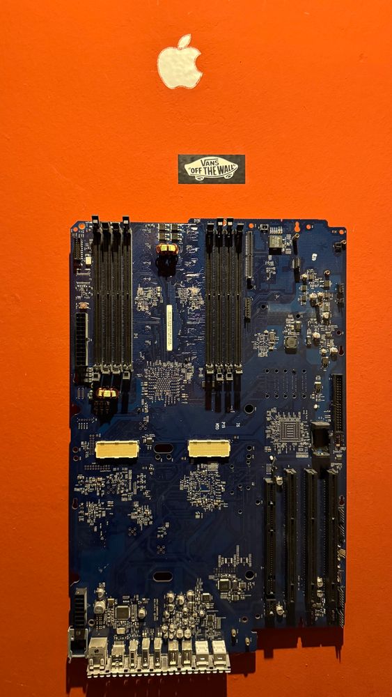 Mainboard eines Mac Pro G5 hängt an einer orangenen Wand.
