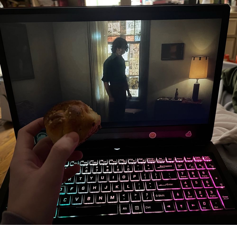 image of my hand holding a garlic knot in front of a laptop playing season 2 episode 5 of iwtv
