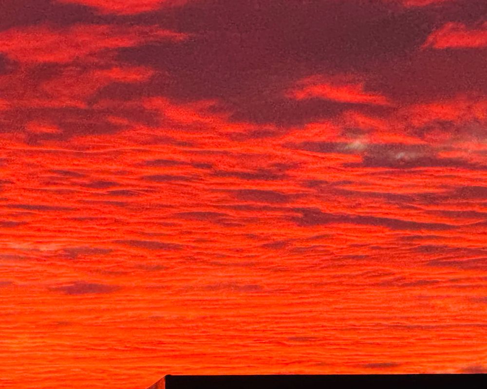 Bright red sky at sunset as soon over the top of a roof. That area is around the Golden Gate Bridge and the Marin Headlands.