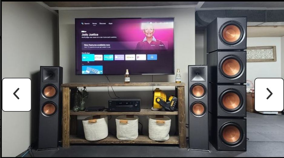 home speaker arrangement with two floor stand speakers on either side of the television, and four subwoofers stacked atop each other next to the right speaker.