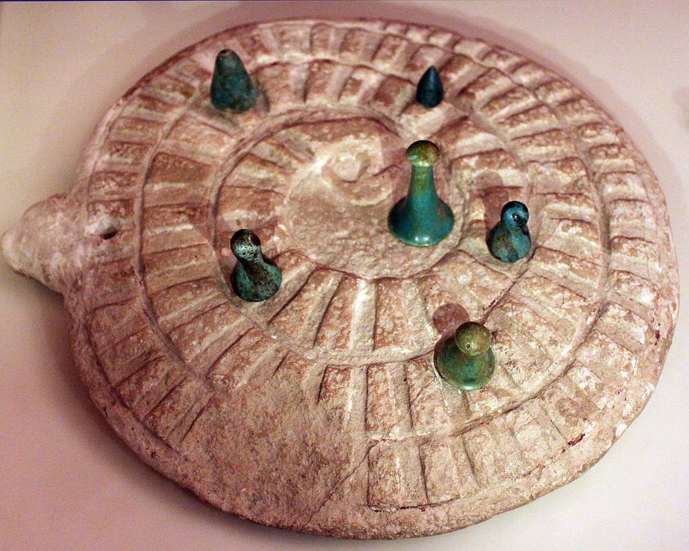 Photograph of an ancient Egyptian mehen game board with playing pieces.