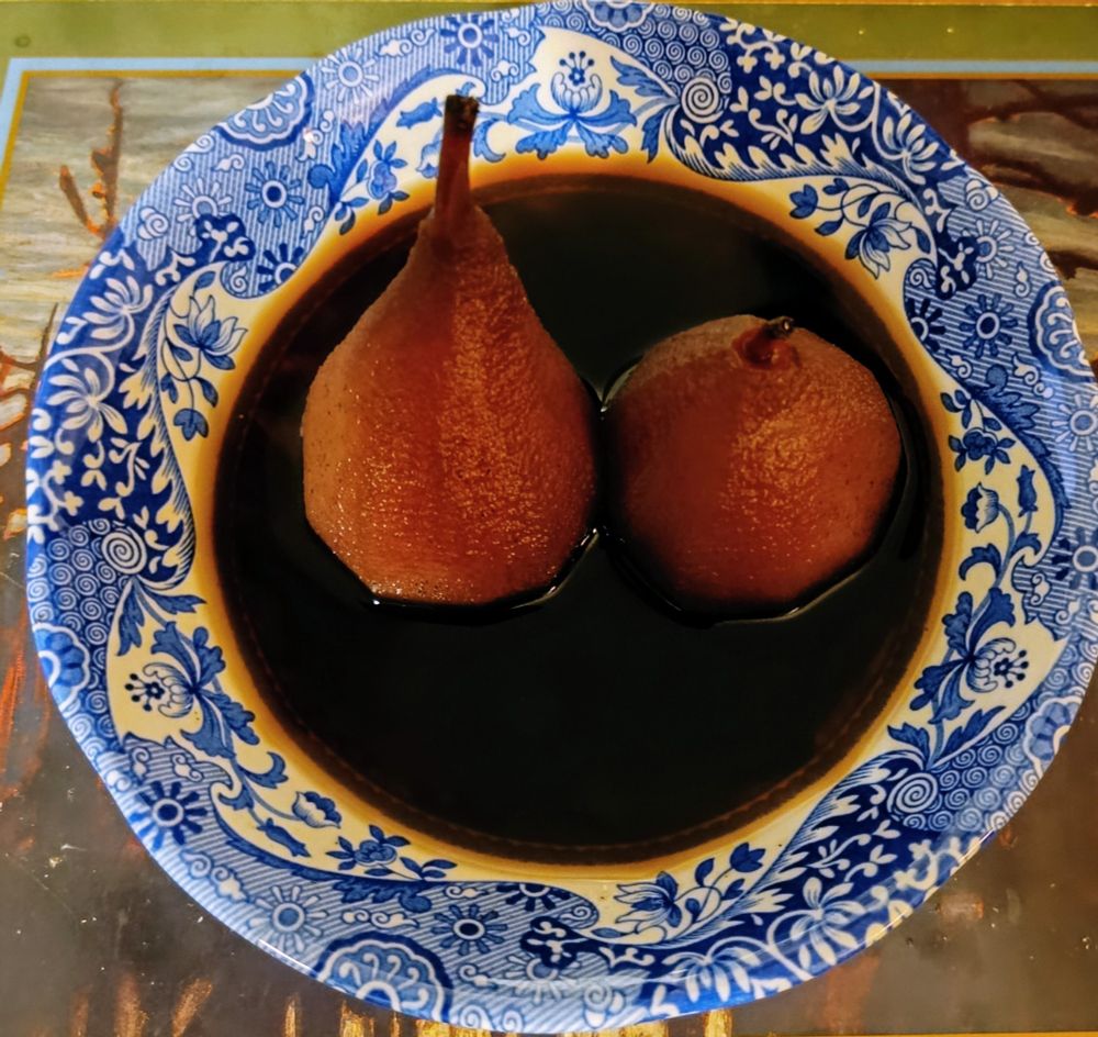 Picture of two pears poached in red wine in a bowl 