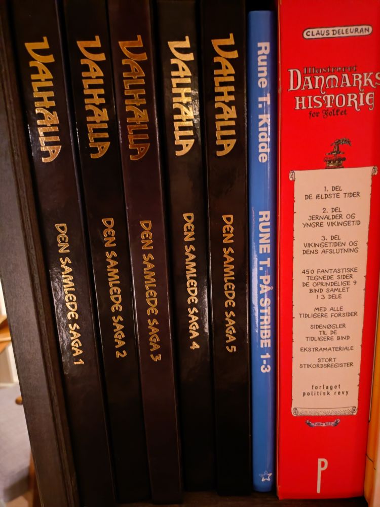 En bogreoler med alle 5 bind af Valhalla Den Samlede Saga, ved siden af Rune T. Kidde: Rune T. Pp Stribe 1-3 og Claus Deleurans Illustreret Danmarks Historie for folket