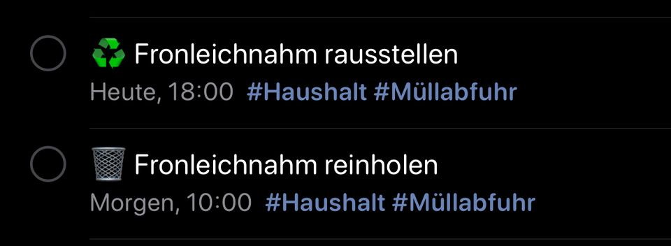 Screenshot aus der Apple Erinnerungren-App, die zwei Aufgsaben zeigt. Die erste hat den Text "Fronleichnam rausstellen" mit der Zeitangabe "Heute, 18:00" und den Hashtags "#Haushalt" und "#Müllabfuhr". Die zweite Nachricht enthält das Symbol eines Mülldepots und den Text "Fronleichnam reinholen" mit der Zeitangabe "Morgen, 10:00" und den gleichen Hashtags.