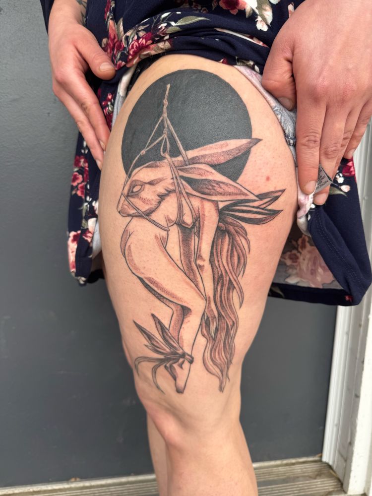 tattoo of a woman hanging in shibari face down with a large rabbits head tied to her back