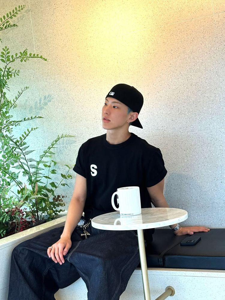 hoshi sitting on a bench with a mug on a table in front of him