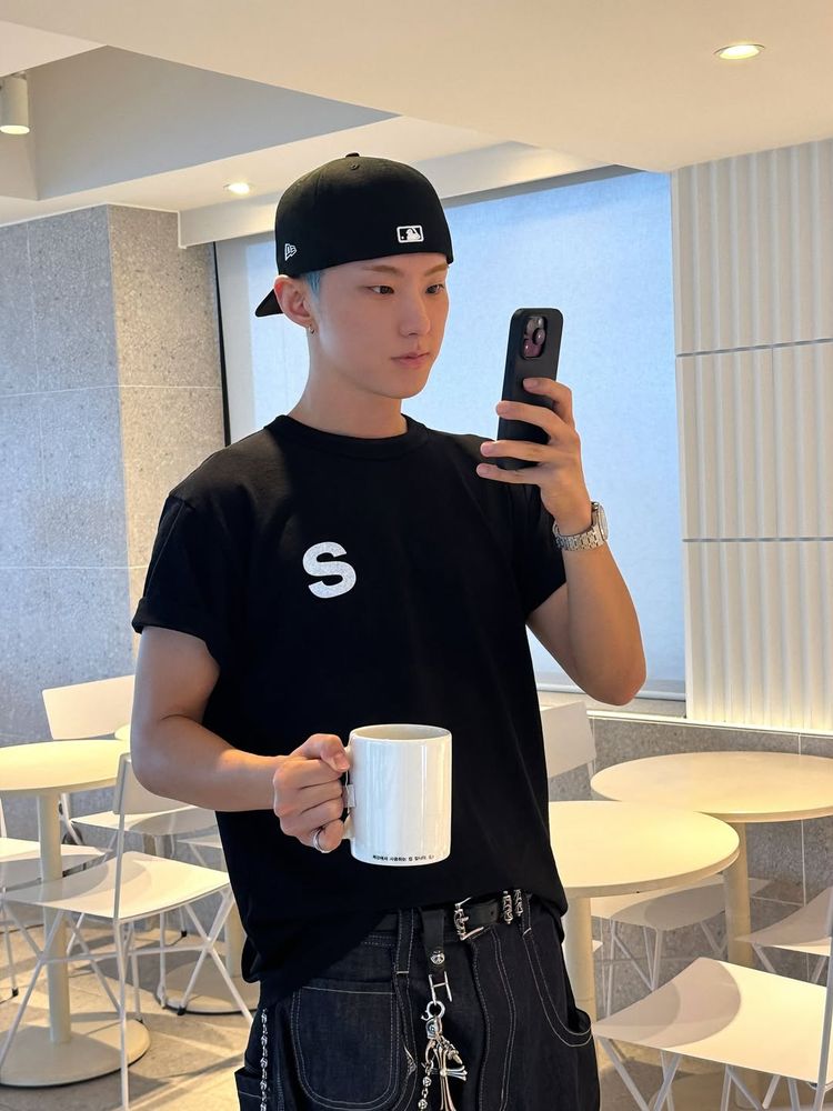 hoshi holding a mug and taking a photo on his phone