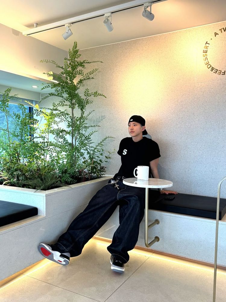 hoshi sitting on a bench with a mug on a table in front of him
