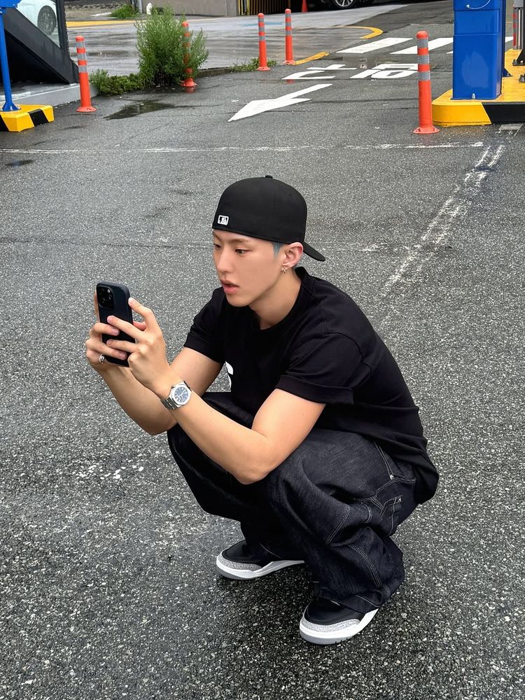 hoshi crouching down outside and looking at his phone