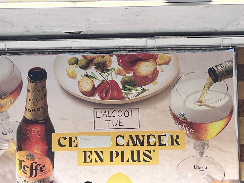 Affiche publicitaire pour une marque de bière, dont le slogan a été modifié pour le remplacer par "ce cancer en plus", avec un bandeau "L'alcool tue" évoquant les "fumer tue" des paquets de tabac.