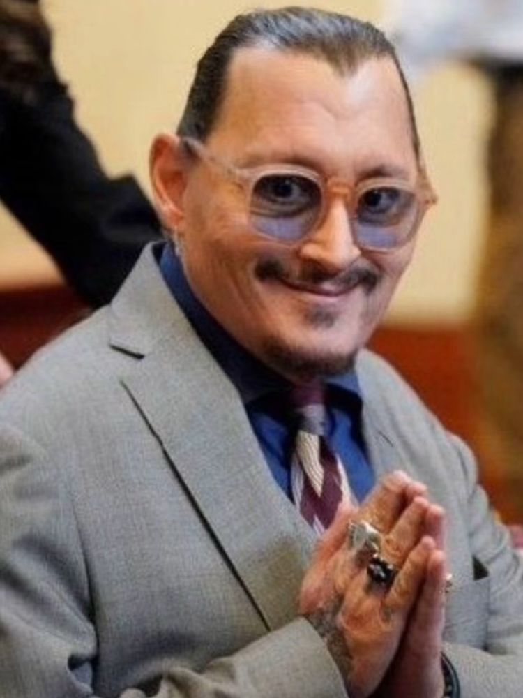 A man with receding hairline, a stupid goatee and a weak mustasch, putting his hands together like mr burns, wearing roommate rings, a bluish gray suit with a striped tie and some ugly glasses