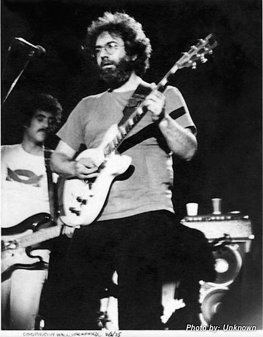 Jerry Garcia plays guitar, John Kahn stands behind him