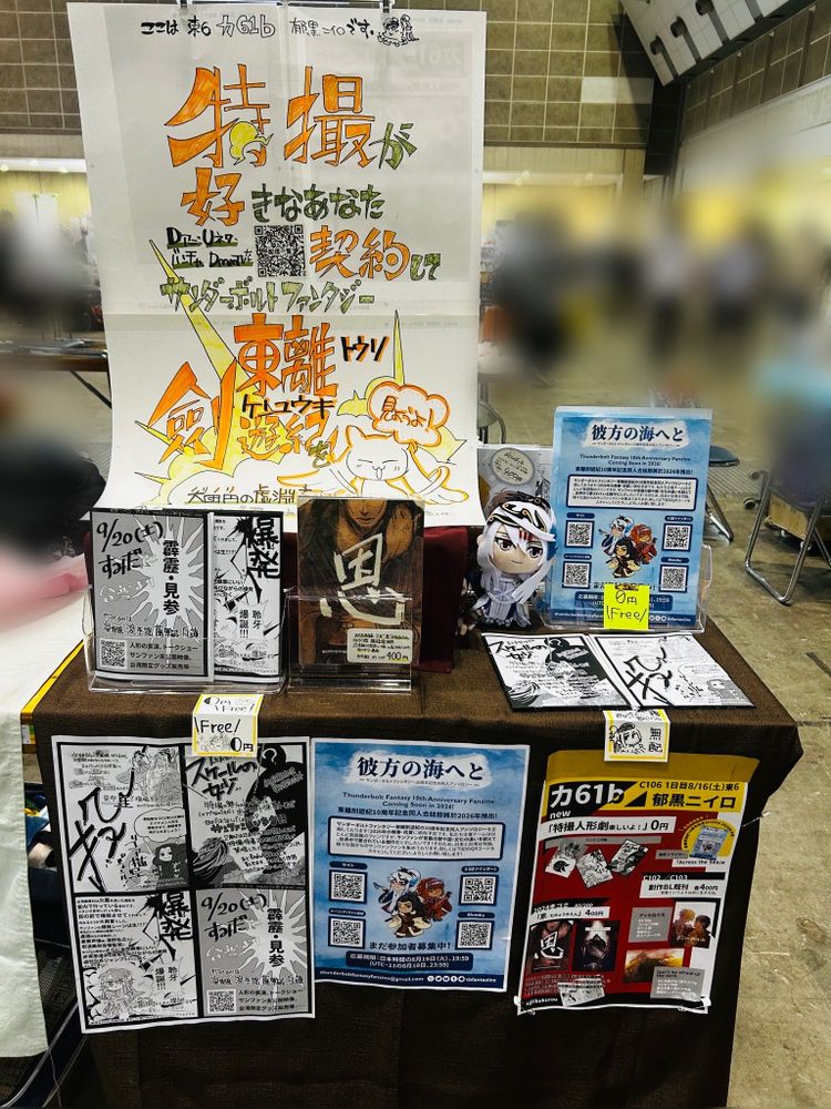 同人繪師郁黒在Comic Market 106的攤位。在攤位有大的手工宣傳海報，郁黒的同人誌合免費列印本，和東離劍遊紀10周年記念同人合誌的傳單。

