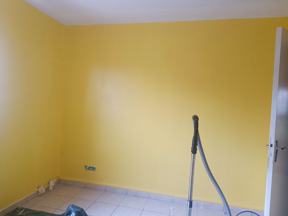 Une photo d'une pièce en travaux. On voit deux murs, récemment peints en jaune.