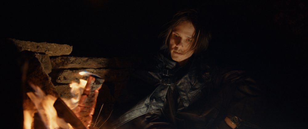 A photo of me wearing black, sitting next to a campfire in the night.