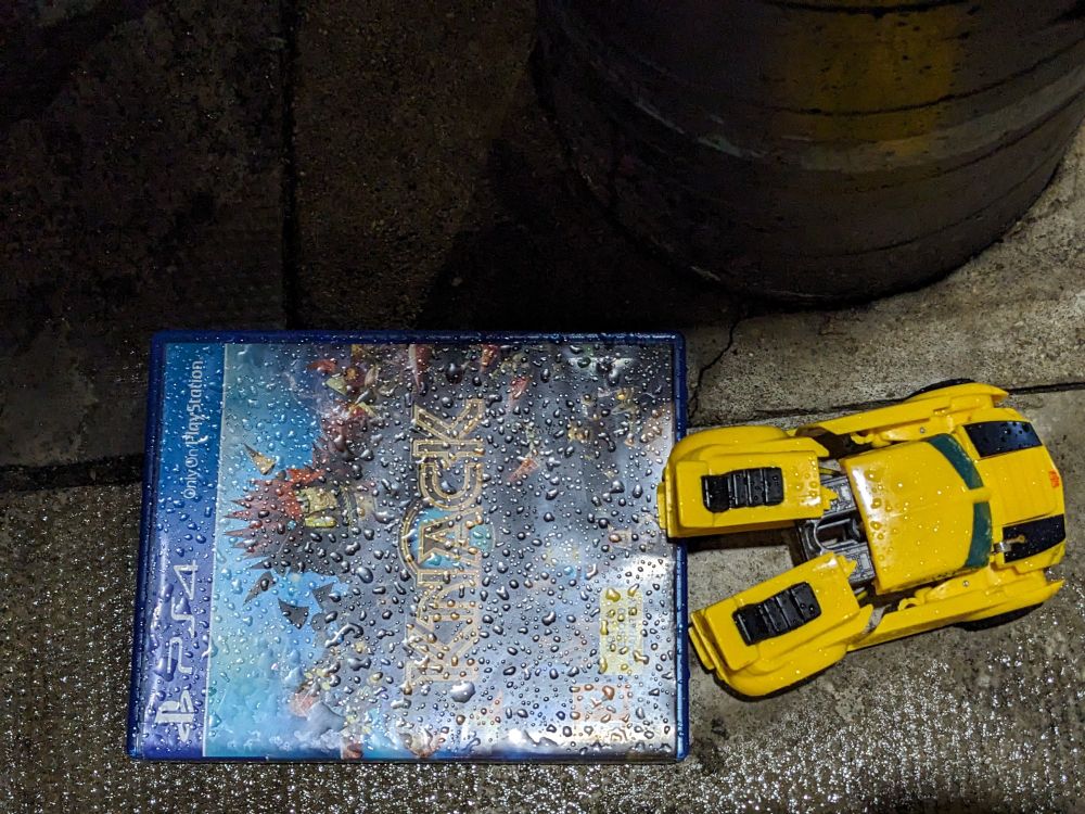 A copy of ps4 exclusive Knack, discarded on the pavement of a rainy street 