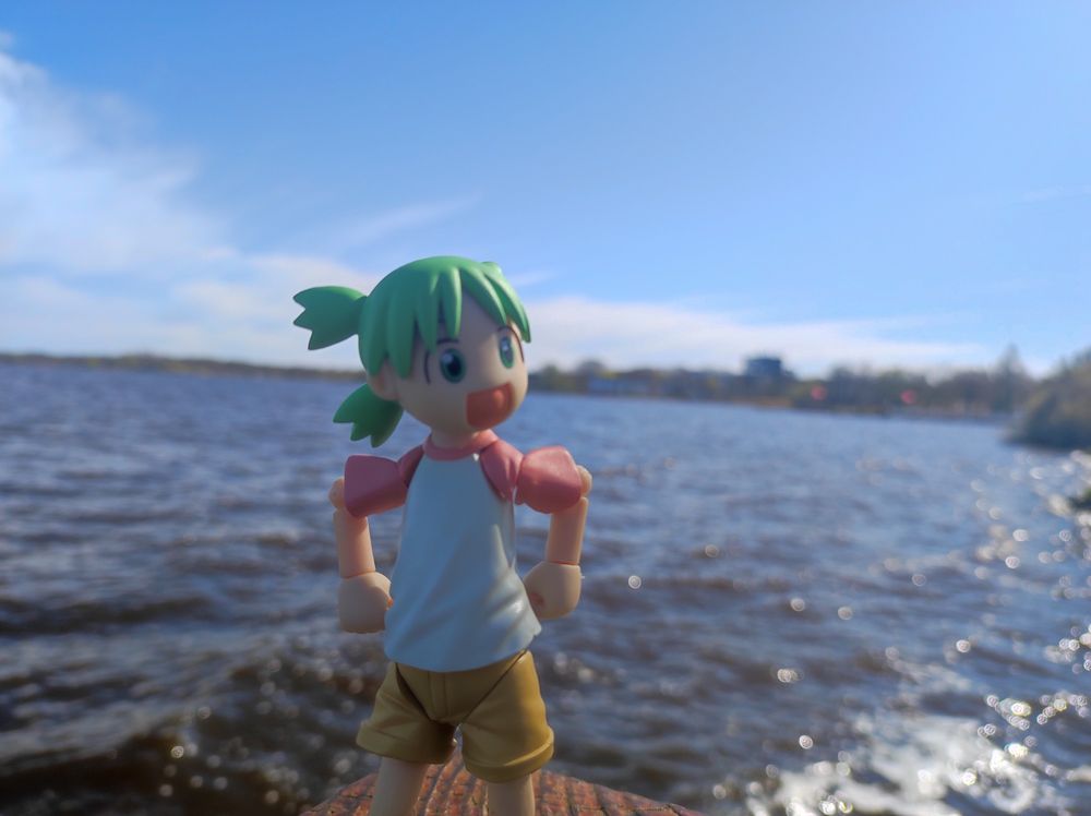 Yotsuba posing in front of a lake, with her hands on her hips.
