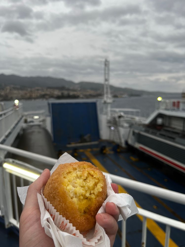 Ein angebissenes Arancini vor einem Intercity Notte auf der Fähre über die Strasse von Messina