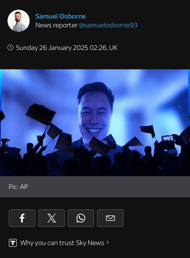 Elon Musk addresses a crowd on a big screen