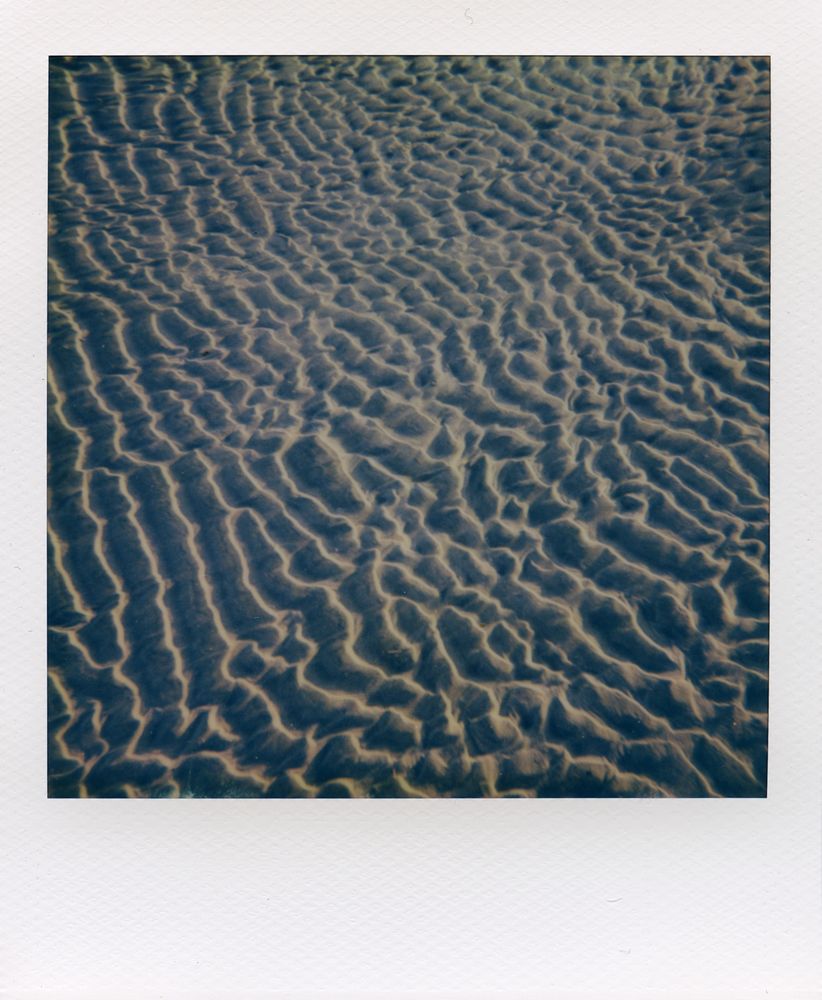Polaroid picture of the patterns in the sand from the waves rolling in and back out
