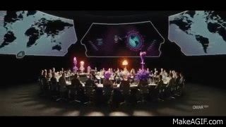 From the 2014 movie The Kingsman starring Colin Firth & Samueal L Jackson: a group of men sit at a circular table in a large grayish room full of maps & other situations, until colorful mist explosions occur in an artful sequence from their craniums