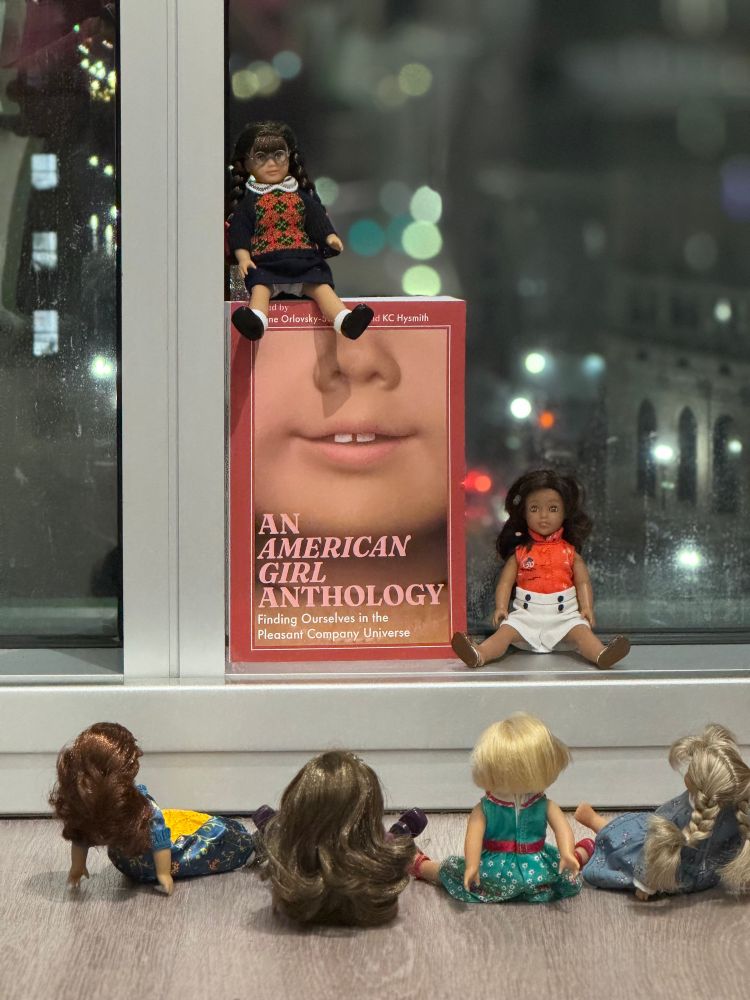 AN AMERICAN GIRL ANTHOLOGY book. Molly sits on it, Nanea sits next to it, and Felicity, Rebecca, Kit, & Kirsten look up from sitting on the floor.