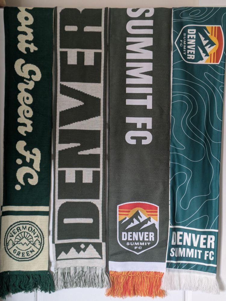 Four primarily green football (world) scarves:

Vermont Green FC
Denver NWSL
Denver Summit woven
Dunver Summit fleece (with excellent contour lines).

Missing: UVM's scarf.
