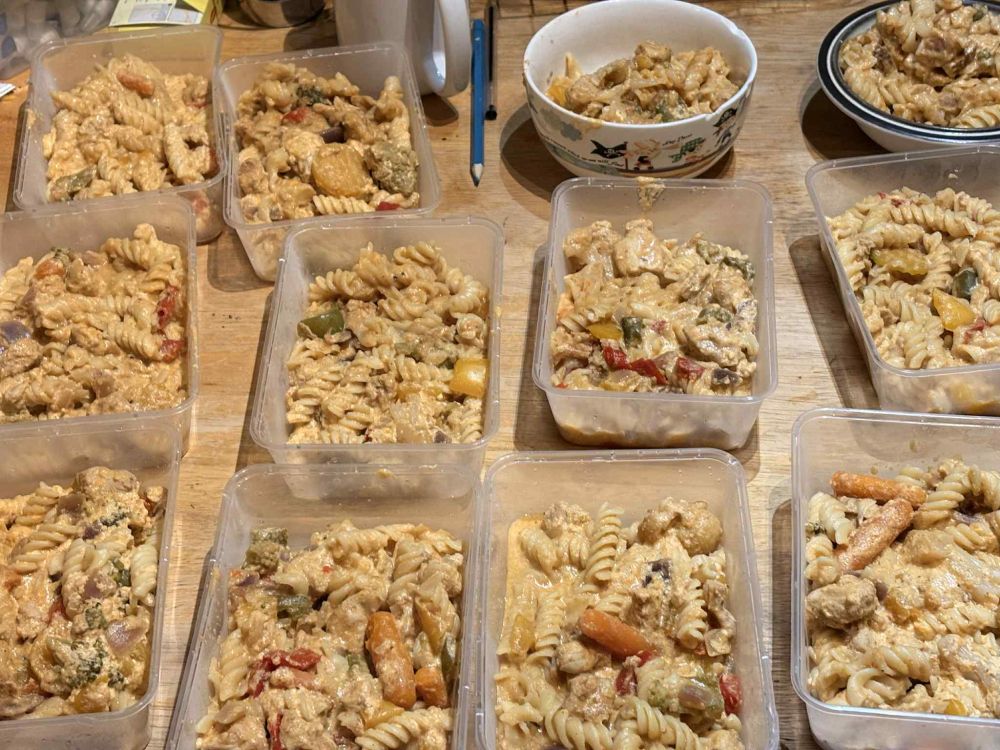 10 plastic containers and 2 ceramic bowls, arranged in 3 rows of 4, each containing a buffalo chicken cheese mix