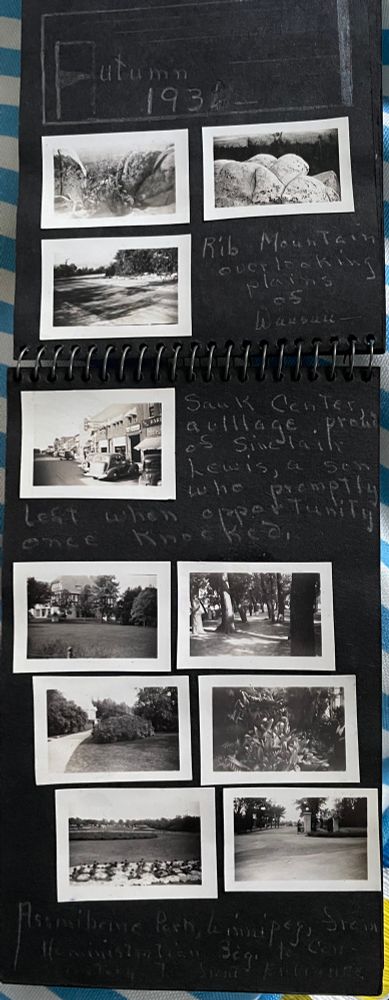 A black page with very small black and white photos pasted on it. The photos are of bushy landscapes and a town street and are frankly not very good. Near the top, in silvery pencil is the handwritten caption from this post