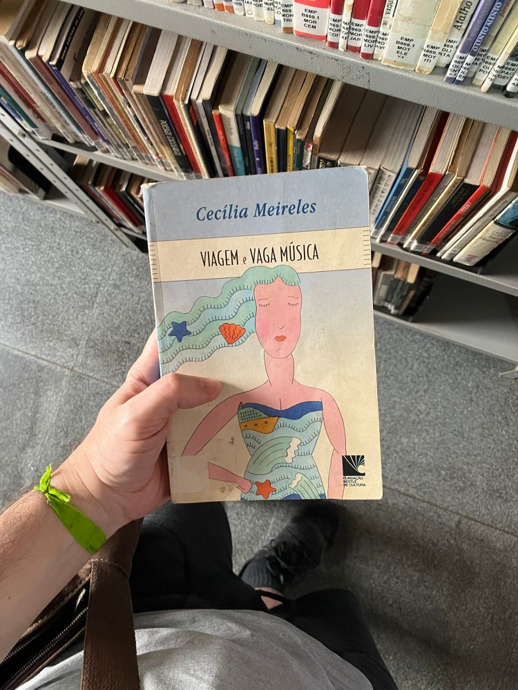 Capa do livro de poemas “Viagem e Vaga Música”, Cecília Meireles. Na capa, desenho de uma mulher branca com cabelos e vestido de ondas do mar, sendo visível estrelas, conchas e um navio.
