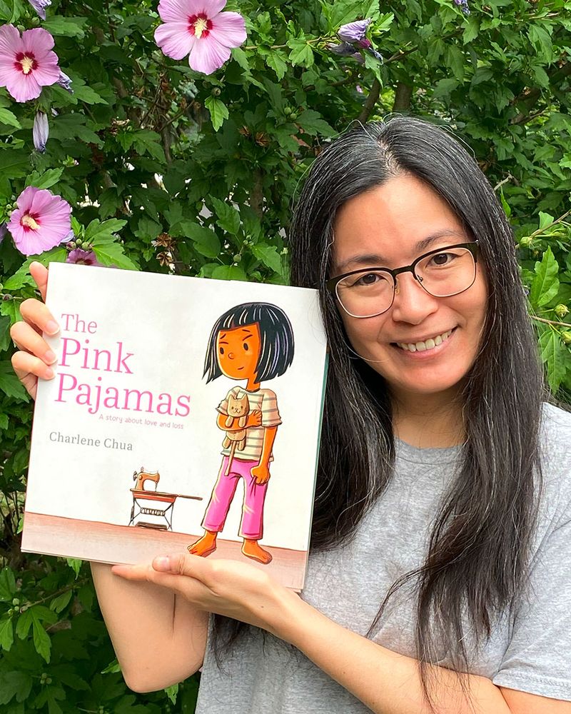 Photo of author and illustrator Charlene Chua holding up a copy of their book, the Pink Pajamas