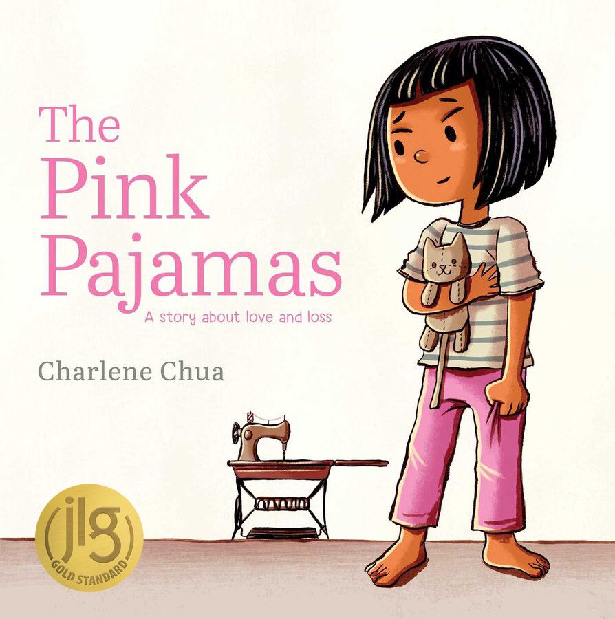 Cover art for The Pink Pajamas with the Junior Library Guild selection gold seal. Art features a young Asian girl wearing pink pajamas, looking off at an old style manual sewing machine.