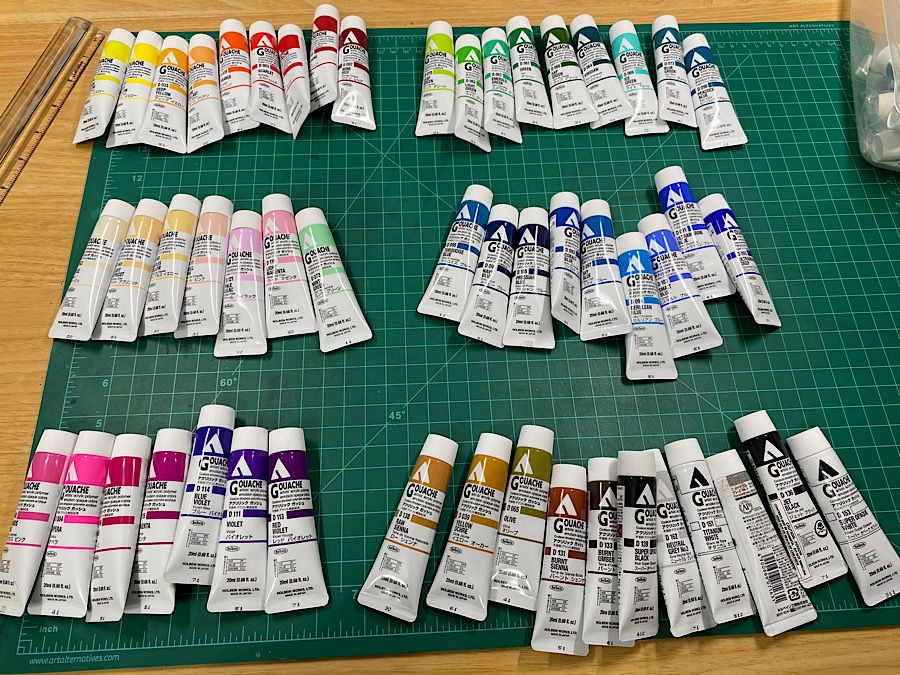 Many tubes of Holbein acryla gouache. All of them are now loose. They are grouped together into smaller groups by color range.