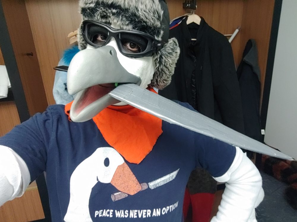 A weirdo dressed as a bird with a cardboard knife in his beak while wearing the goose with a knife meme shirt "peace was never an option."