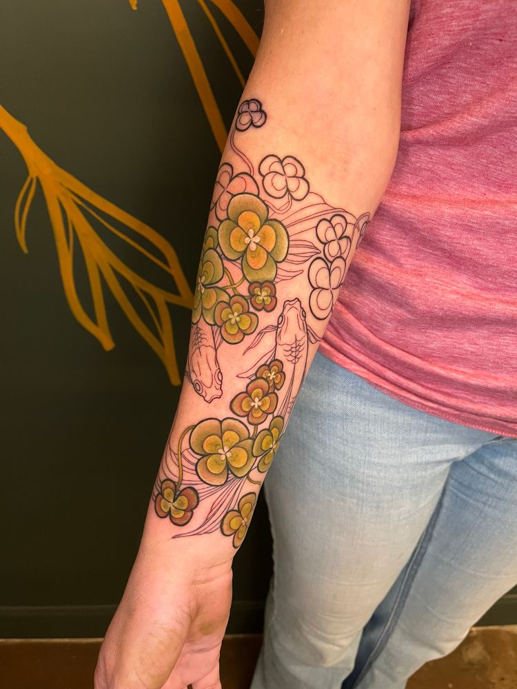 Inner forearm angle of koi fish swimming under some water clovers 