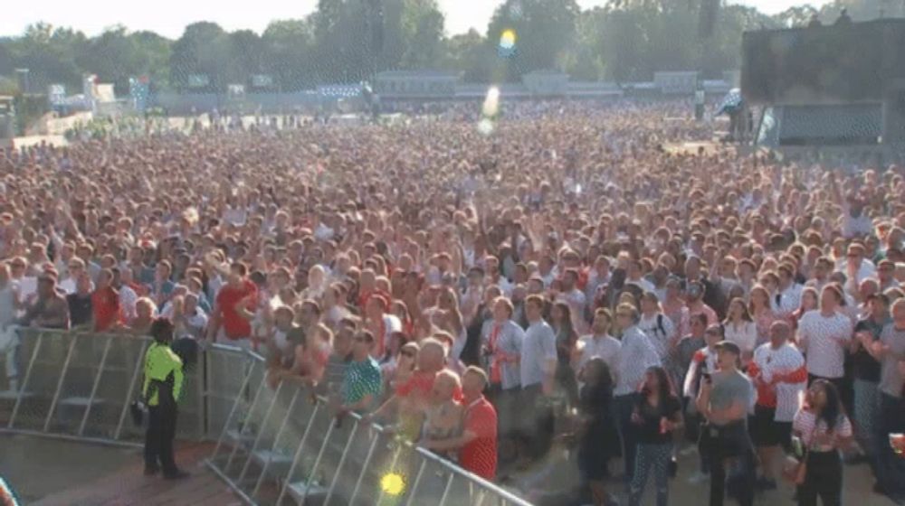 a crowd of people standing in front of a fence at a festival