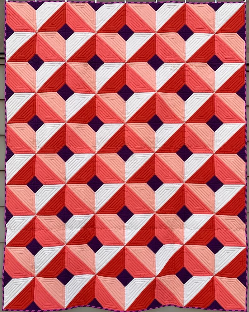 Description: Each year, I construct a quilt using the Pantone color of the year. For the 2019 color of Living Coral I decided to create a quilt using a value scale surrounding the key color. I drew on my experience as a scenic painter for the theatre to emphasize value in a manner that creates the illusion of dimension in the finished design. Five colors of quilting thread were used to match each fabric color to maintain focus on the pieced design.